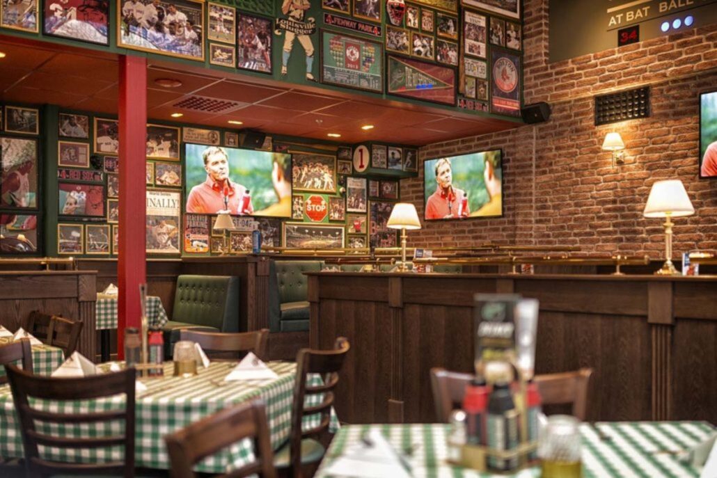Spiseområde på O'Learys Drammen med grønne rutete duker, sportsdekor på veggene og TV-skjermer som viser sport.